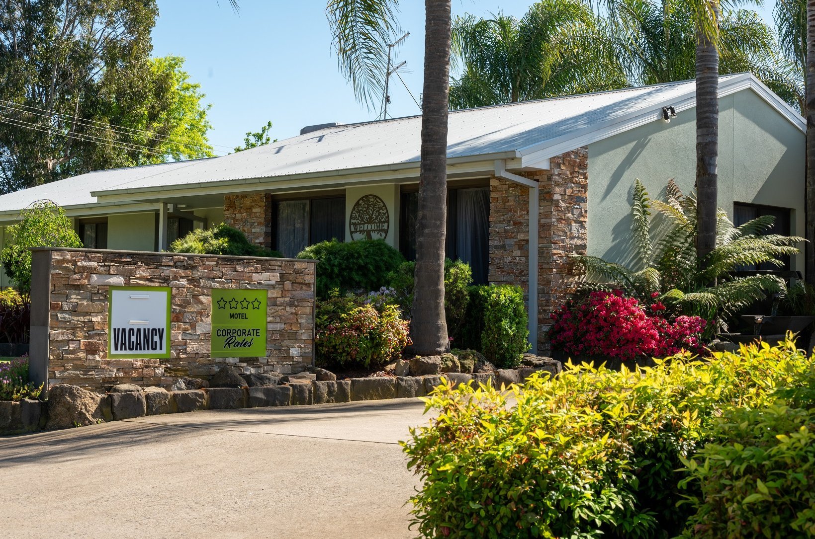 River Gums Motor Inn entrance with stone features, flowering gardens, and corporate rates signage