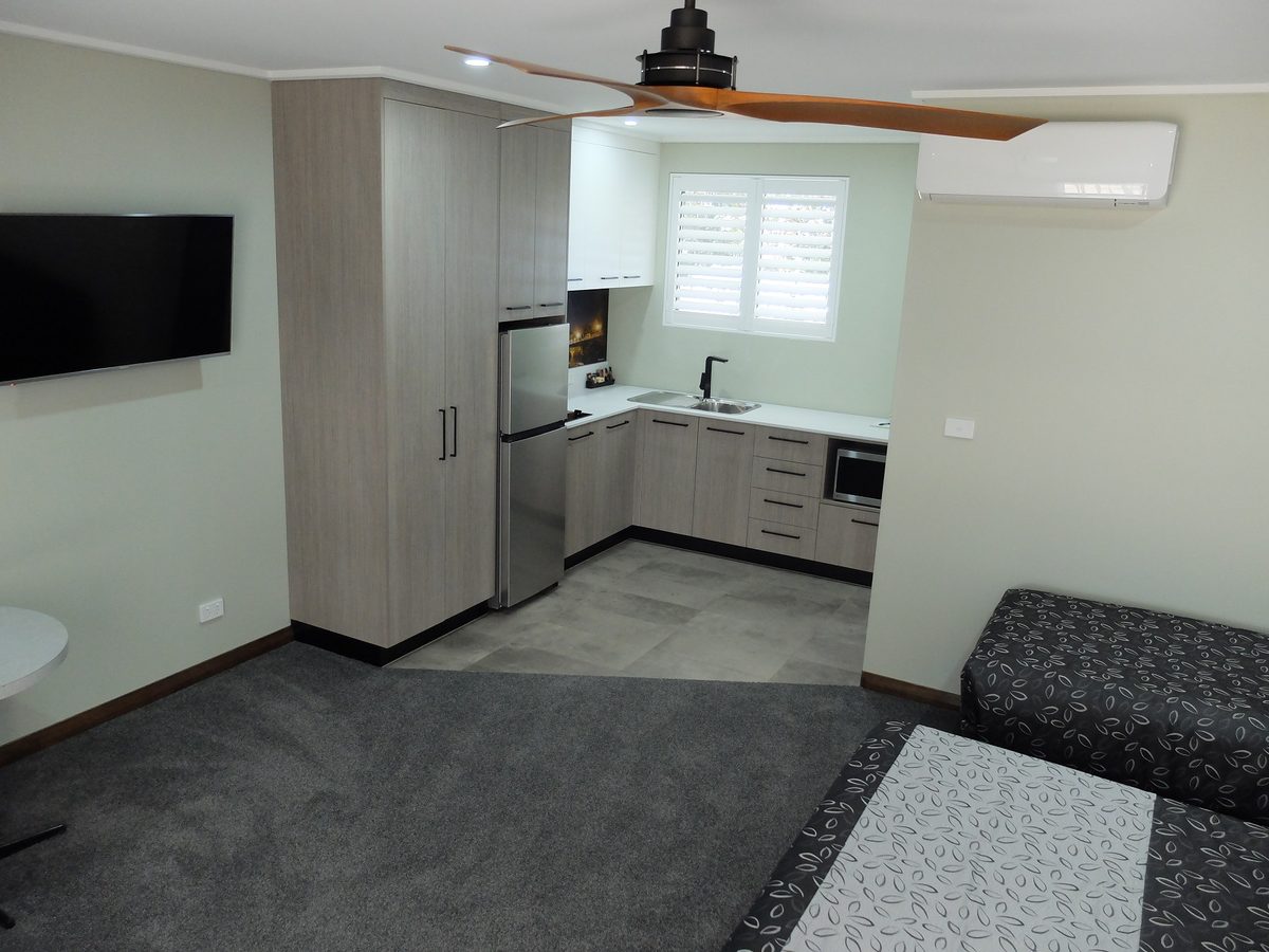 Studio Apartment with queen bed, kitchenette, and modern ceiling fan